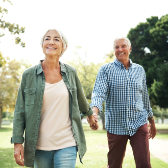 A retired couple walking through a park.