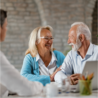 Couple smile as advisor shares how a Schwab Genesis Variable Annuity™ can offer cost-effective growth and protected income.