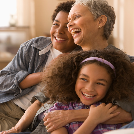 Woman laughs as she hugs her grandson and granddaughter.