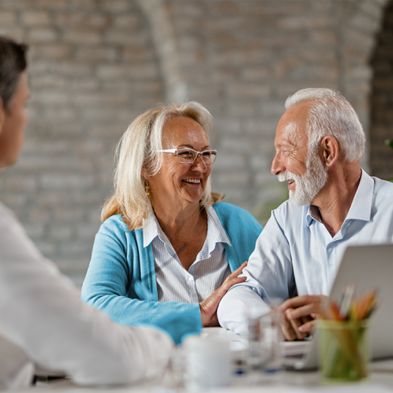 Couple smile as advisor discusses Schwab Genesis Advisory Variable Annuity’s choice of investment options.