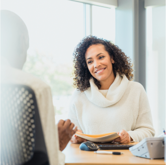 The client, sitting across the desk from her advisor, smiles as they discuss Schwab Genesis Advisory Variable Annuity investment options.